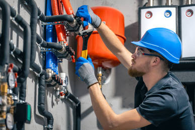 Plumbing technician inspecting water heater pipes and fittings
